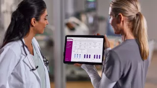 Two female healthcare professionals look at data on an tablet
